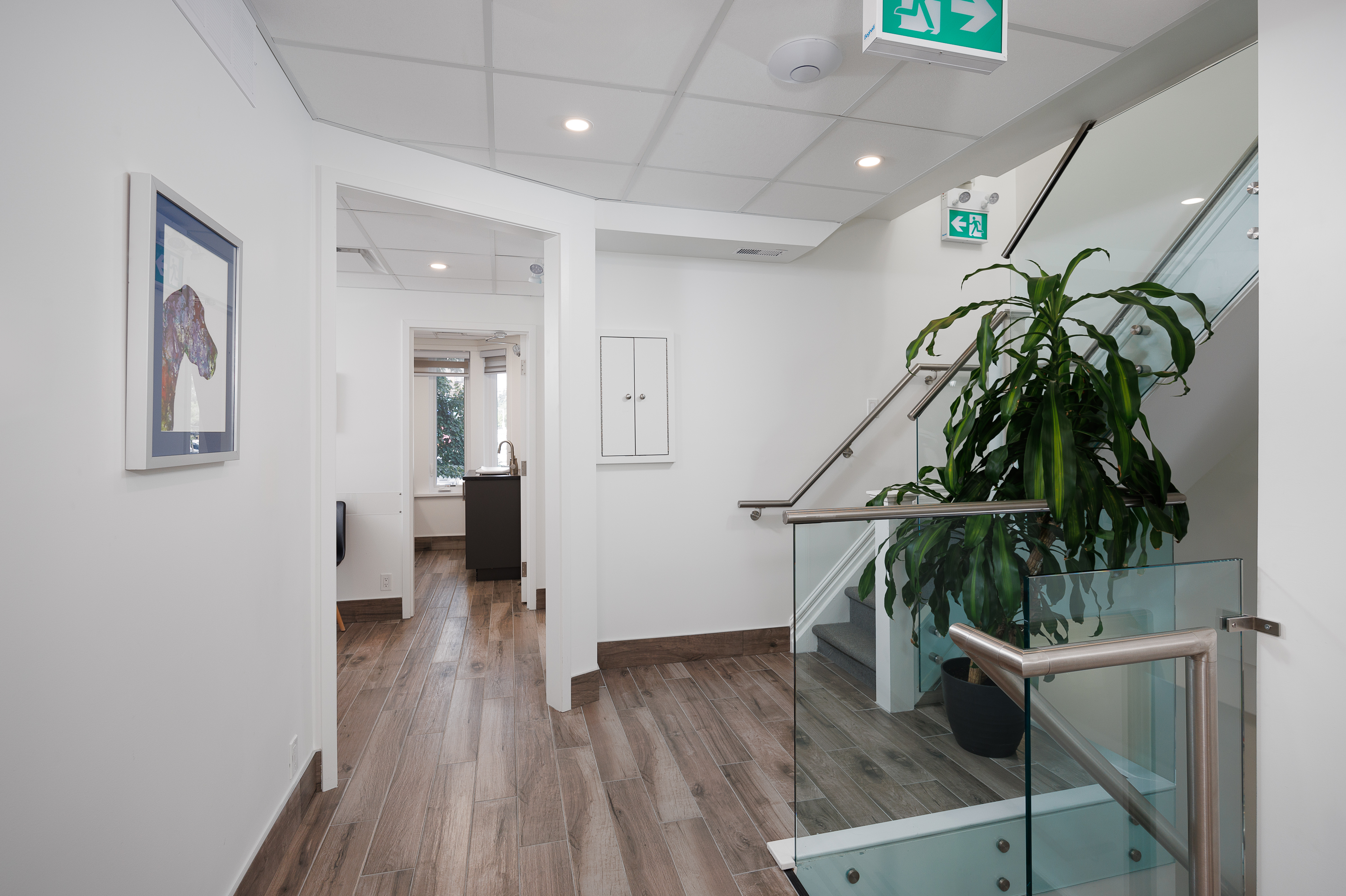 The image shows an interior space with a modern staircase leading to an upper level, featuring a clean, well-lit environment with white walls and a sleek design aesthetic.