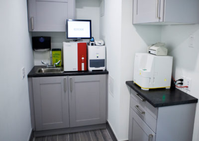 A small, well-organized office space with a computer monitor, printer, and various other items on a countertop.