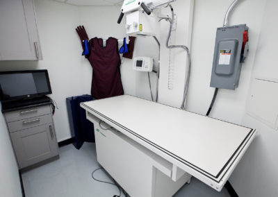 The image depicts an interior view of a medical examination room with various equipment and supplies.
