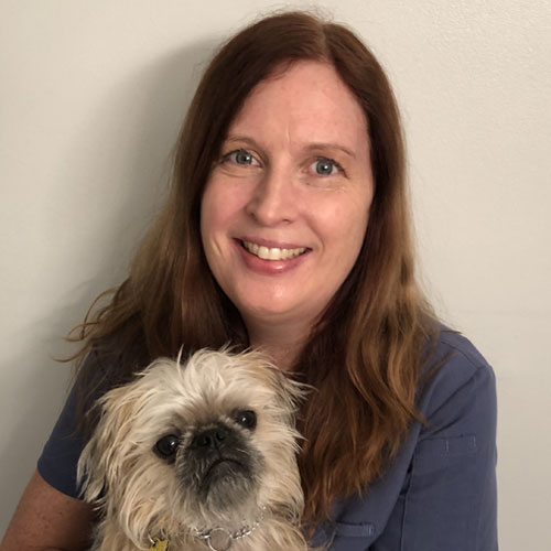 A woman holding a small dog with a smile on her face.
