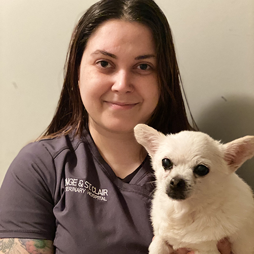 A woman holding a small dog in front of her chest.